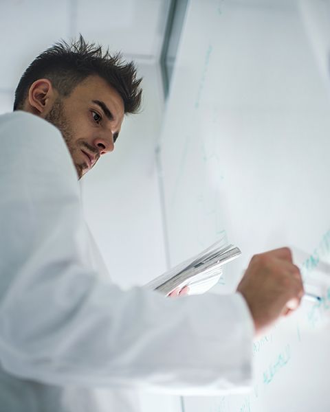 Resident physician, a white male, at a whiteboard writing the 5 things he can do to ensure he gets a fair offer. 