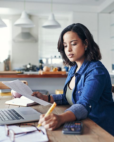 A physician, a Black woman, casually dressed in her home office on her laptop searching for jobs on PS&D's website.