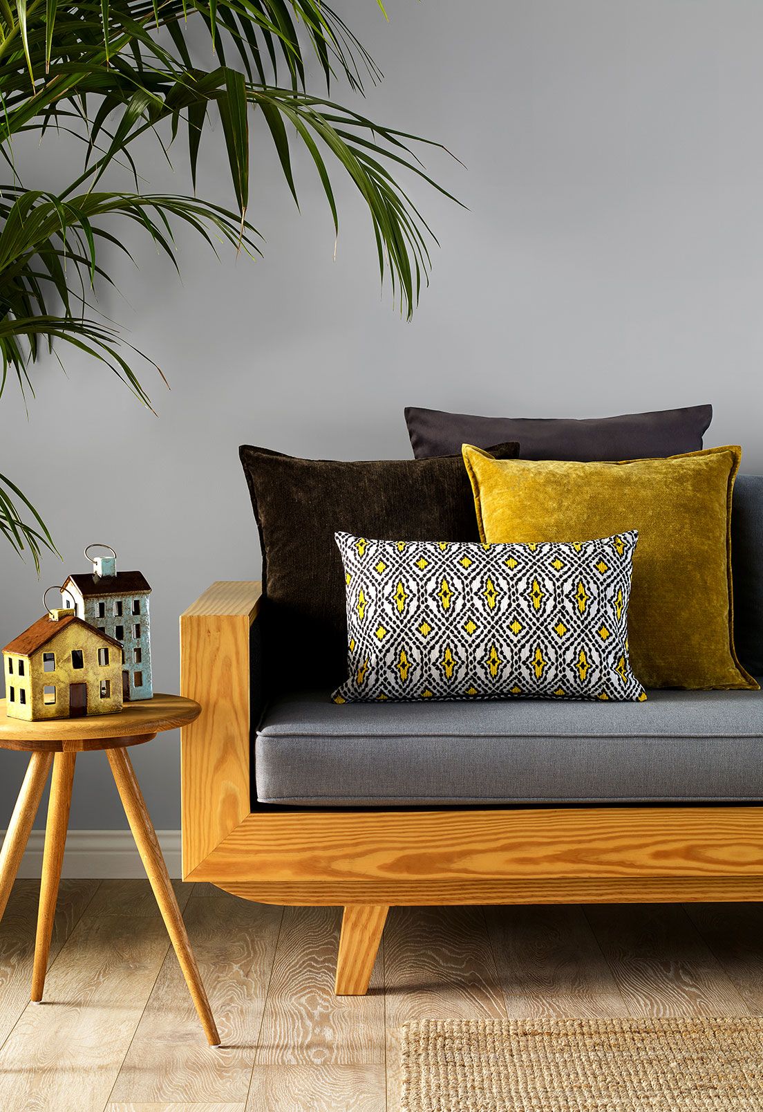 Representing telehealth is a living room with a modern grey and wooden sofa with yellow accent pillows.