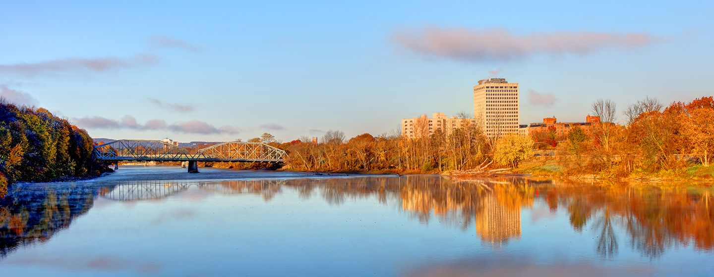 A river with a city and bridge in the background in Binghamton, NY.