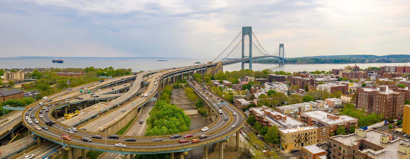 Skyline view of New York City's highway and Brooklyn Bridge in the background.