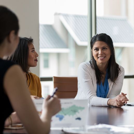 Multiethnic group of physicians, all are women, in meeting smiling and happy.