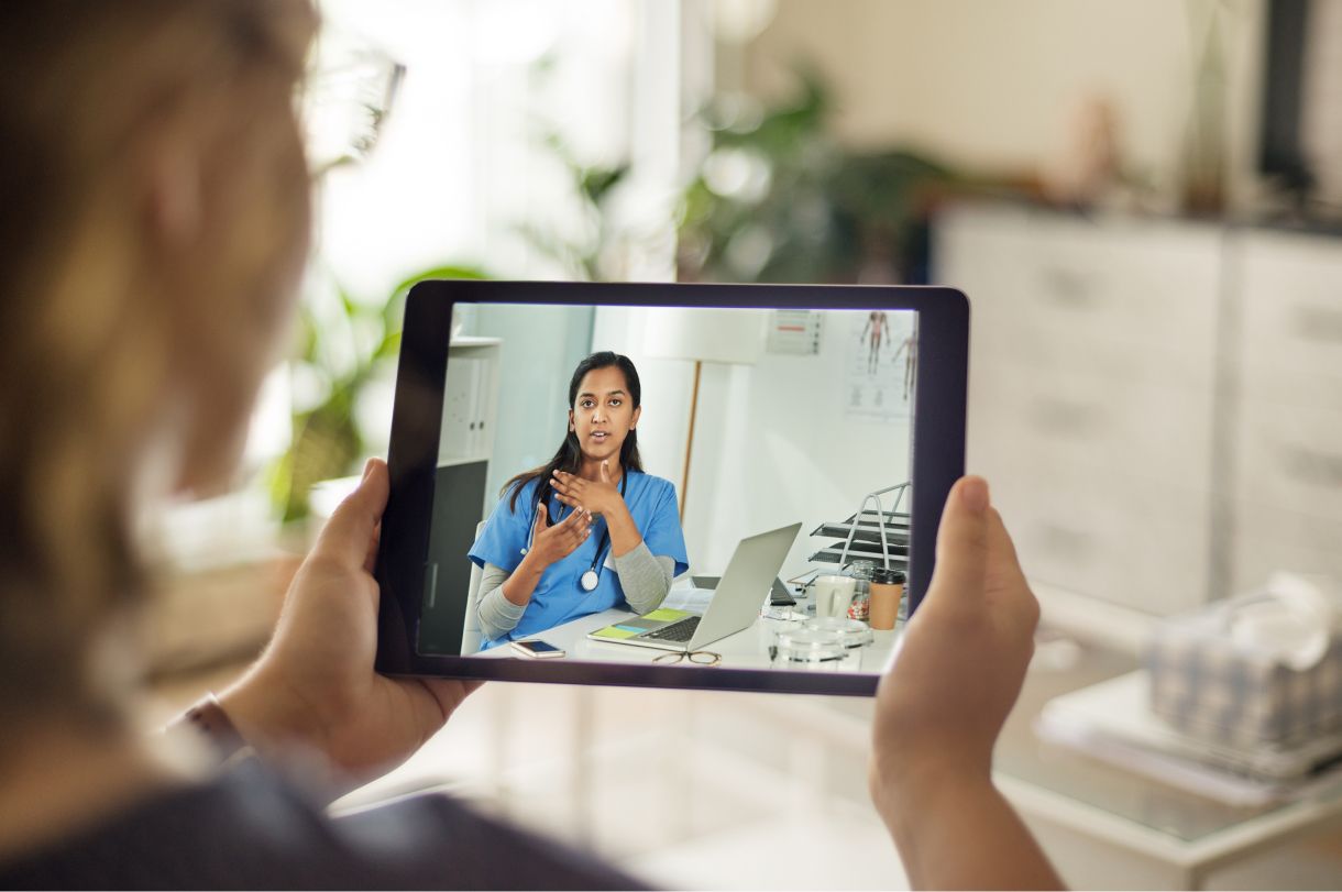 A patient, a white woman, talking with her physician, an East Indian woman, via a tablet.