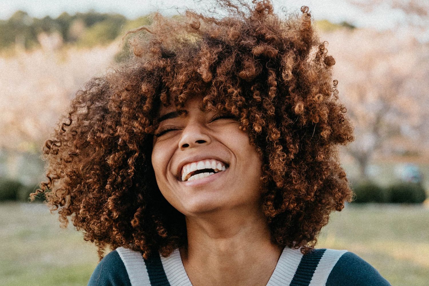 A physician, a Black woman, in natural curls, smiling and happy because of PS&D's career coaching. 