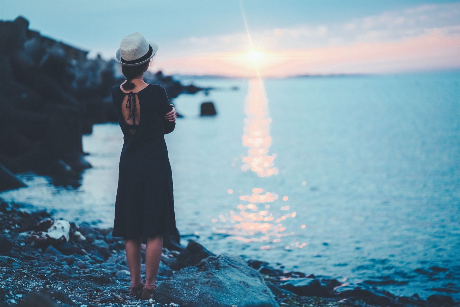 A physician, a Hispanic woman, casually dressed standing at sunset in front of lake, contemplating her career.